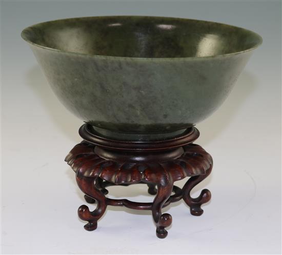 A Chinese spinach green jade bowl, 18th century, diameter 19cm, wood stand